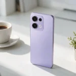 Celular intermediário lilás sobre a mesa ao lado de um café
